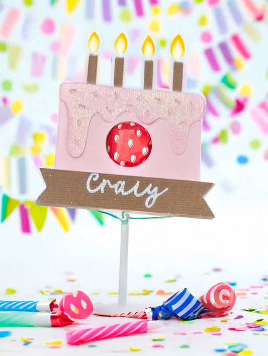 Birthday cake lollipop holder with candles and personalized name tag.